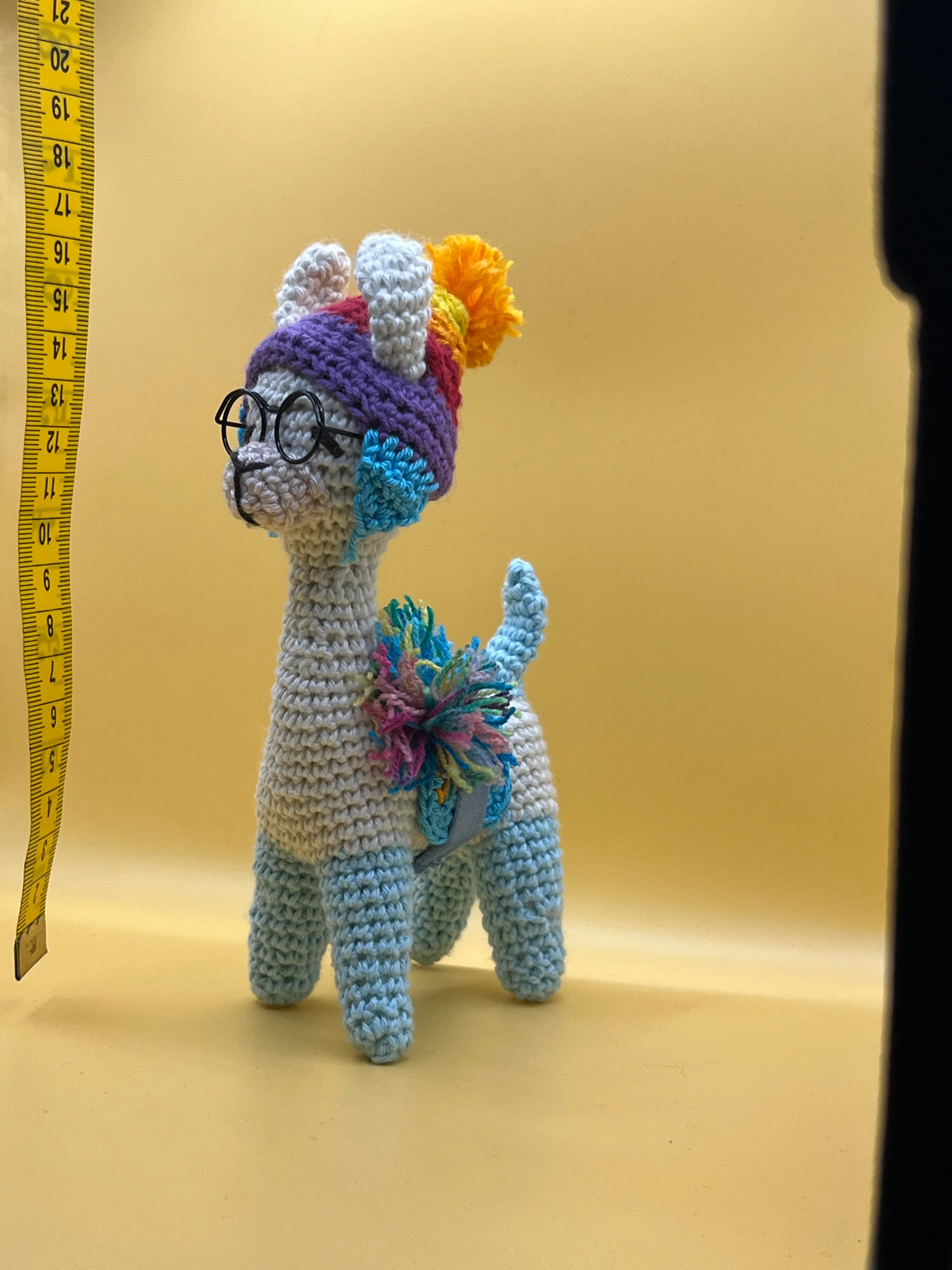 Llama amigurumi showing its round glasses and colourful hat
