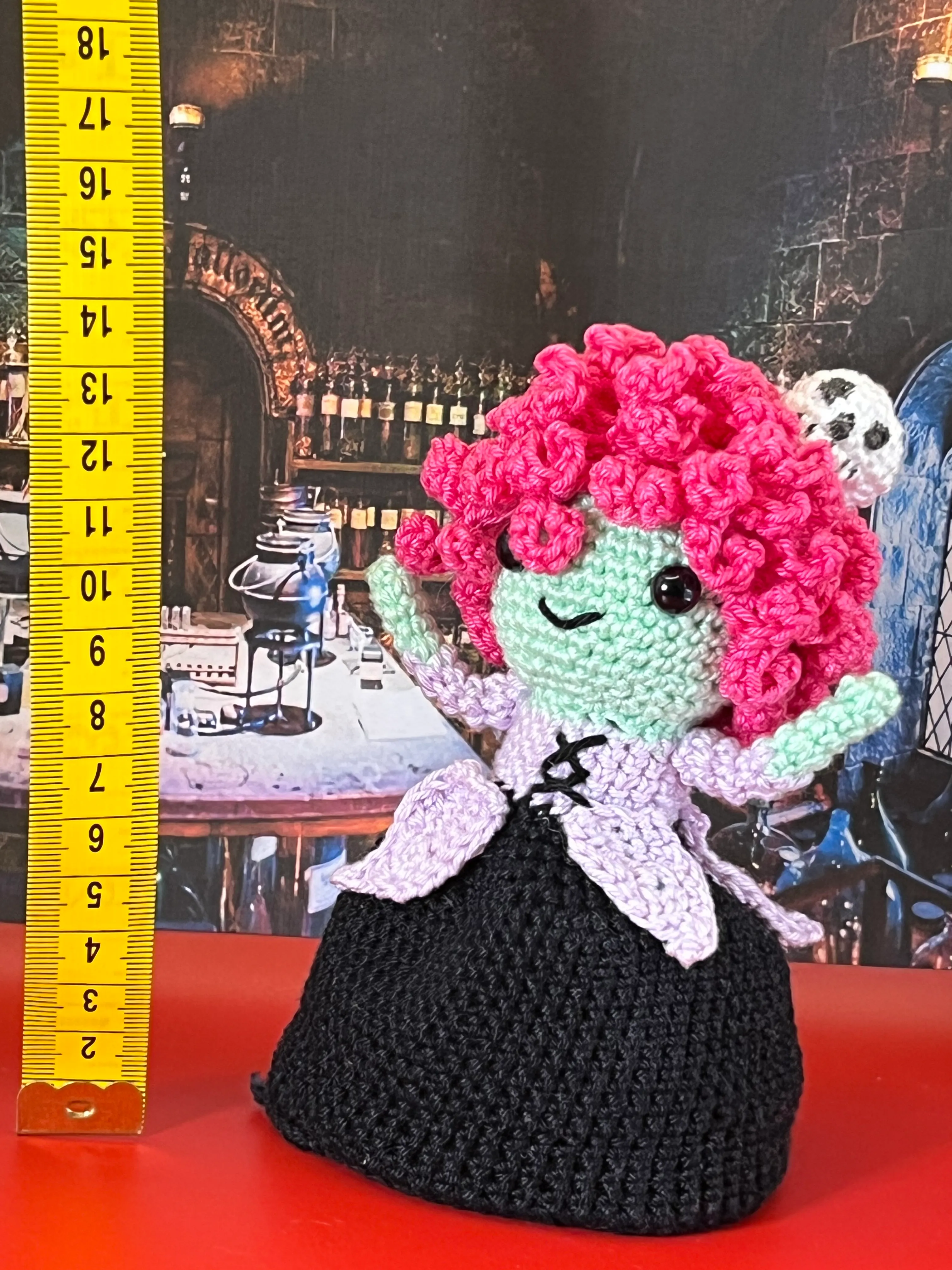 Full view of the crocheted witch beside a measuring tape