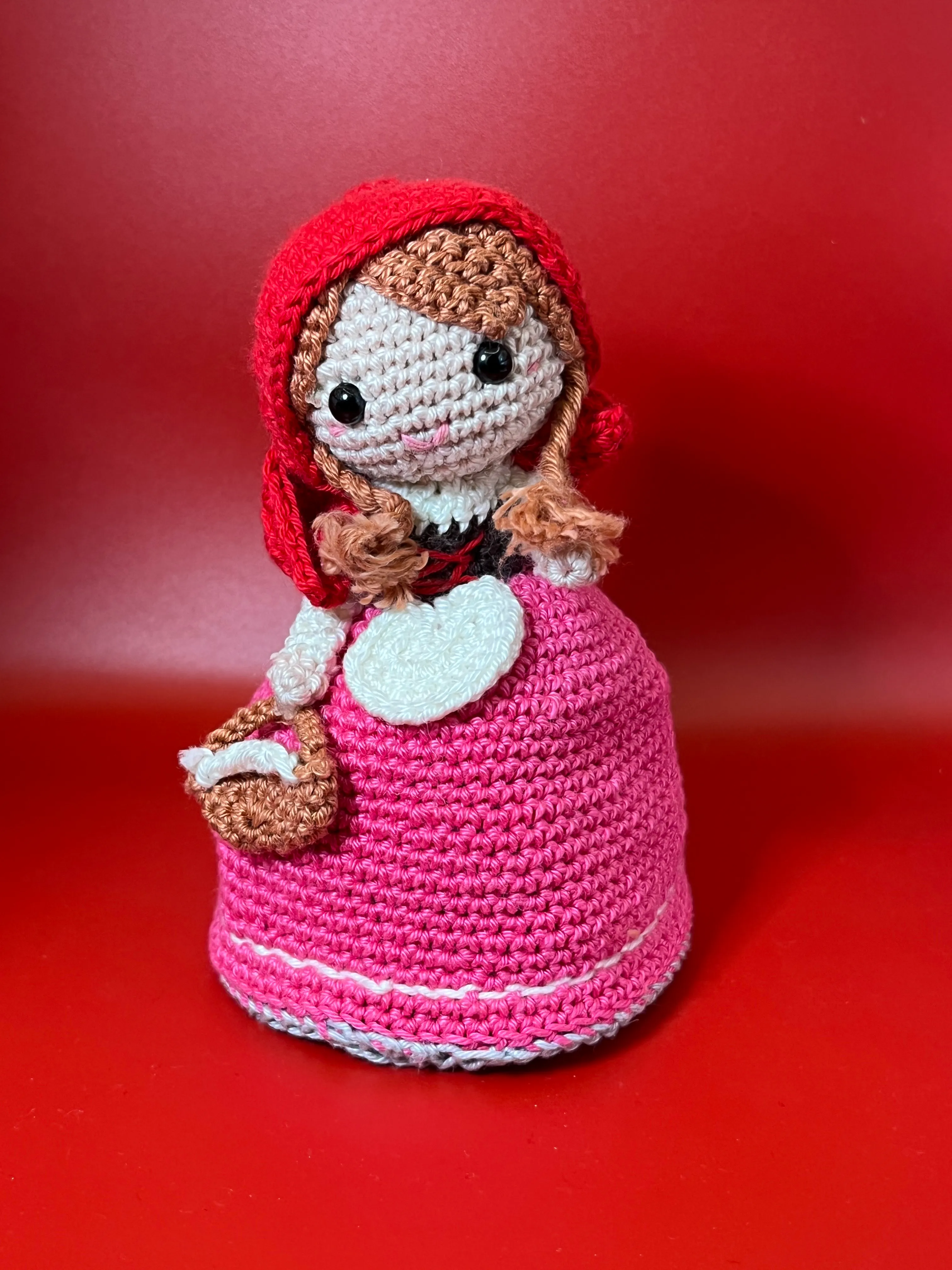 Full view of Little Red Riding Hood’s red cape and embroidered face