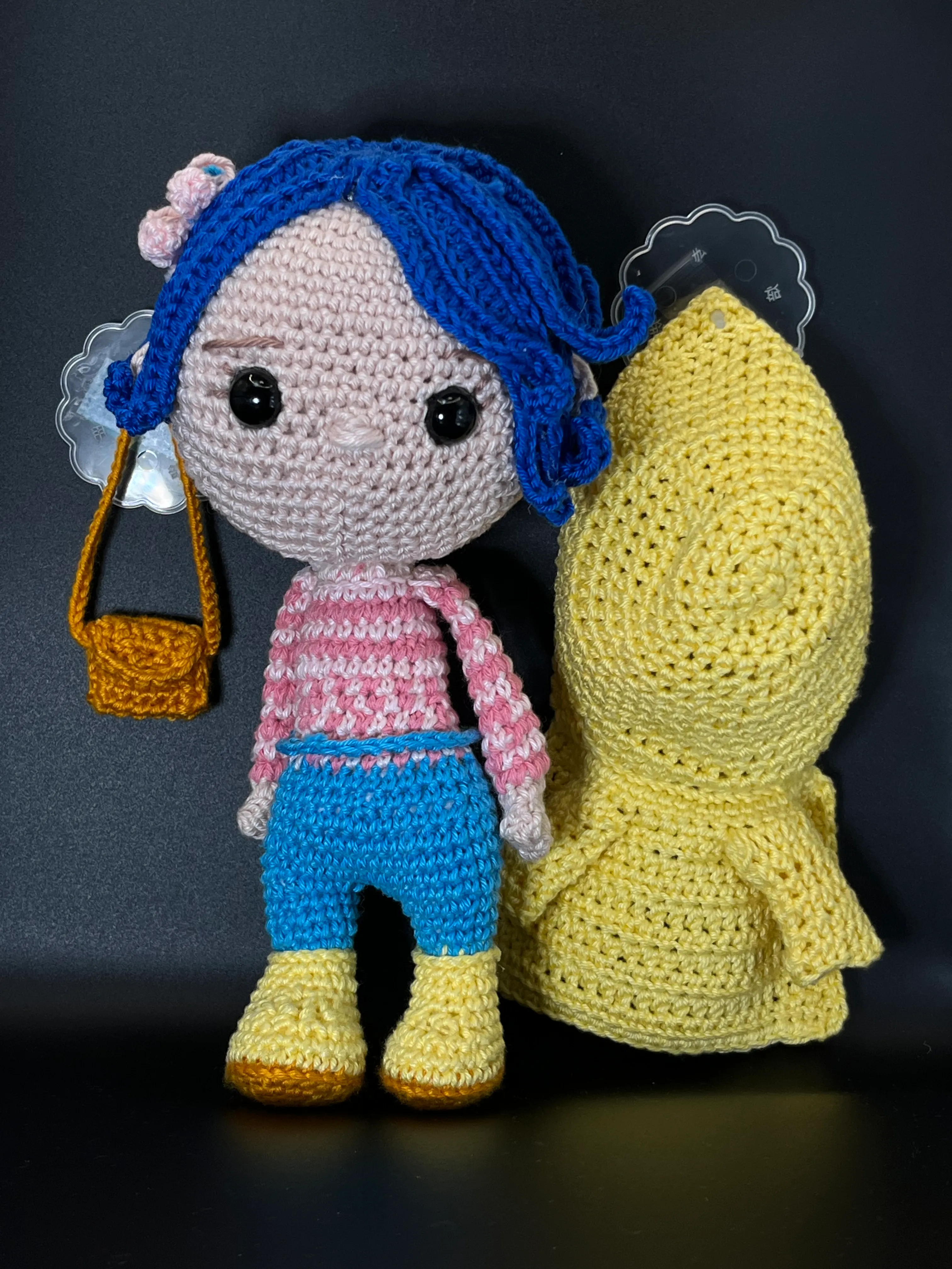 Close view of Coraline’s embroidered face and blue yarn hair
