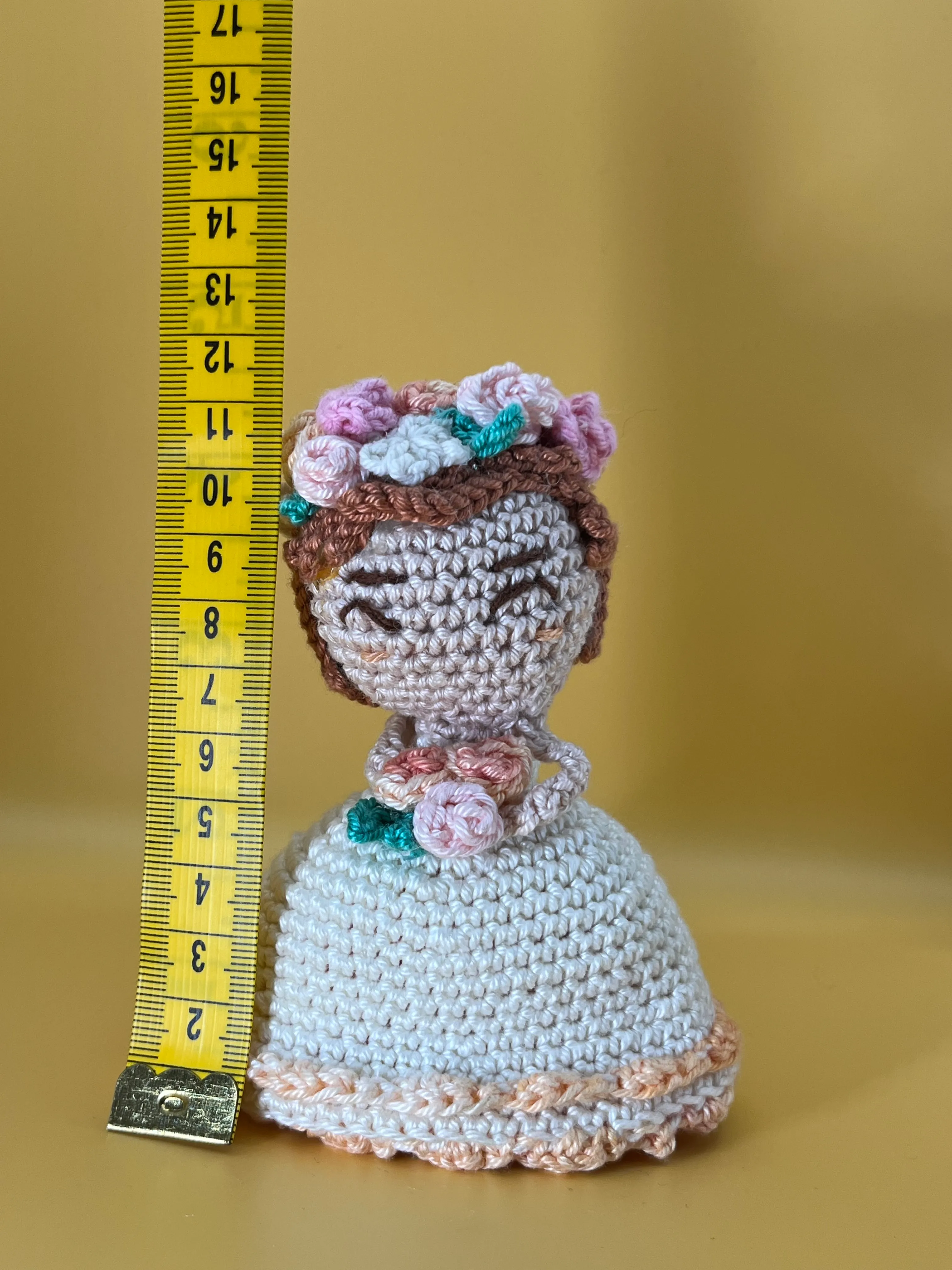 Full view of the crocheted bridesmaid beside a measuring tape